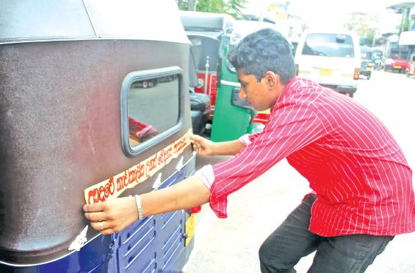 ත්රීවිලර් එකක ස්ටිකර් අලවන තරුණයෙක් මාළිගාවත්තේ දී