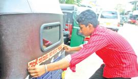 ත්‍රීවිලර් එකක ස්ටිකර් අලවන තරුණයෙක් මාළිගාවත්තේ දී